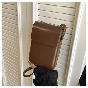 Close-up of a dark brown glossy faux leather crossbody phone bag with a sleek flap closure