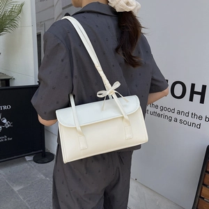 Sac à épaule rectangulaire blanc crème avec nœud décoratif porté par un mannequin