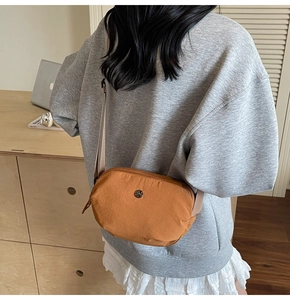 Sac bandoulière en nylon marron porté sur un sweat-shirt gris en situation réelle