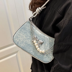 Blaue Glitzertasche mit Perlenkette und Metallschleife, getragen von einem Model
