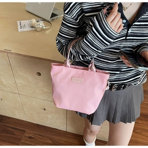 Detailed shot of a pink nylon mini tote bag with fashion label and silk-texture handles