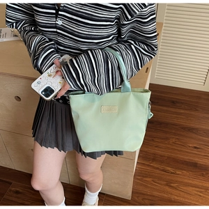 Close-up of mint green nylon handbag with FASHION label paired with a casual outfit