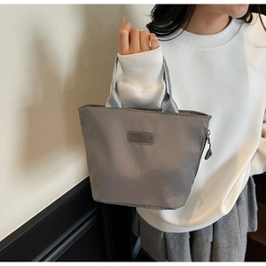 Detail view of water-resistant nylon handbag with sturdy gray straps and zipper closure