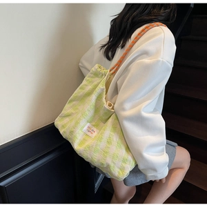 Détail du sac cabas tissé à carreaux verts avec cordon de serrage et bandoulière colorée