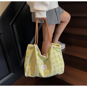 Détail d'un sac cabas à carreaux verts avec poignées en corde et fermeture à cordon