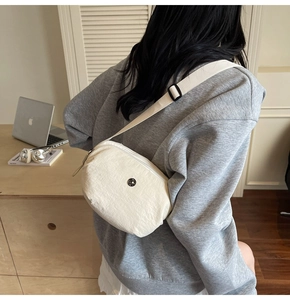 Vue détaillée du sac bandoulière en nylon blanc cassé avec sangle réglable sur mannequin