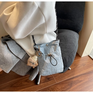 Detail der hellblauen Nylon-Mini-Umhängetasche mit Kordelzug und Plüsch-Anhänger