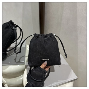 Dettaglio della borsa a secchiello in denim nero con logo in metallo e coulisse