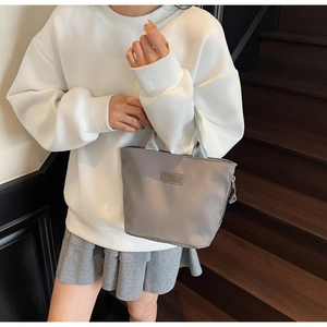 Close-up of grey waterproof nylon handbag with silver zipper and FASHION label