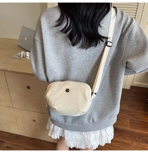 Détail de la sacoche en nylon blanc cassé avec fermeture éclair noire et sangle réglable