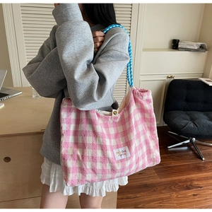 Détail du sac fourre-tout en toile à carreaux roses avec cordon et poignée à rayures bleues