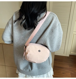 Détail de la sacoche en nylon rose avec texture plissée et logo métallique rond