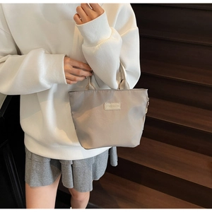 Close-up of silver nylon crossbody bag with Fashion patch on a model at stairs