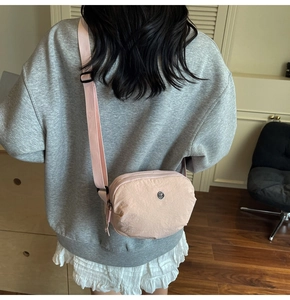 Détail d'un sac bandoulière en nylon rose clair montrant la texture et la sangle
