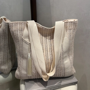 Hollow knit straw beach tote bag with wide canvas strap and tassel in beige