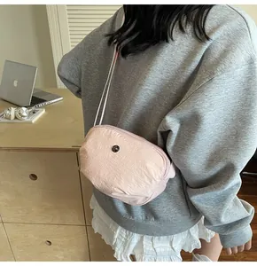 Détail de la bandoulière en nylon rose clair avec badge métallique et texture zip