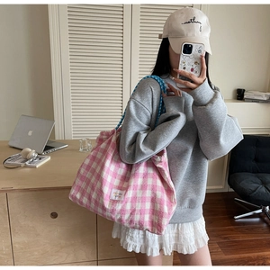 Détail du sac cabas à carreaux roses avec anses en corde bleue et étiquette tissée