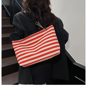 Detail of red and white striped tote bag with gold chain strap on shoulder