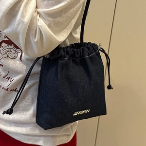 Stylische marineblaue Denim-Beuteltasche mit Kordelzug und Logo am Modell getragen
