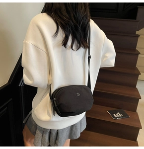 Vue mannequin d'un sac bandoulière en nylon noir avec sangle réglable et logo en métal