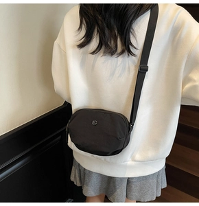 Vue latérale d'un sac bandoulière compact en nylon noir porté par un mannequin femme