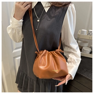 Detail of caramel leather drawstring bucket bag with gold fashion lettering and strap