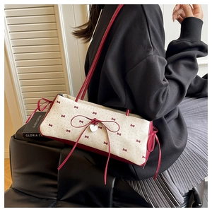 Détail du sac en toile avec nœud rouge, pois et pendentif cœur argenté sur sweat noir