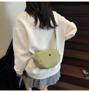 Photo lifestyle d'un sac bandoulière en nylon vert clair sur un mannequin en escalier