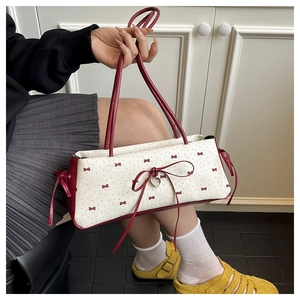 Détail du sac sous le bras en toile avec nœuds rouges et pendentif en forme de cœur
