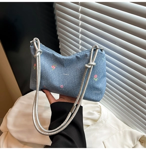 Detail of floral embroidery and knot silver strap on denim shoulder bag