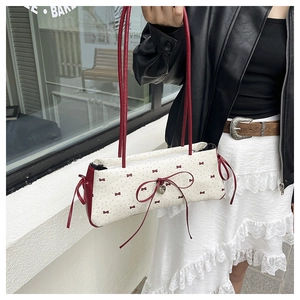 Détail du sac à main crème avec motifs de nœuds rouges, pois et pendentif cœur