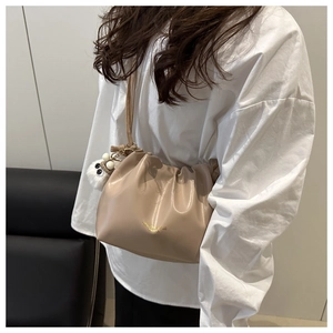 Detail of apricot pleated bucket bag with leather texture and plush ball charm