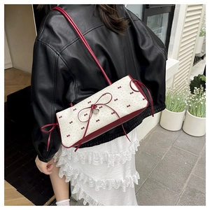 Détail du sac bandoulière blanc à pois rouges et pendentif coeur en métal poli