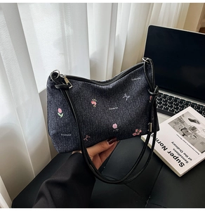 Detail of a denim shoulder bag with floral print held in a cozy lifestyle setting