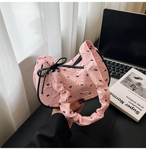 Detail of pink puckered fabric handbag with black bow prints and dainty ribbon accents