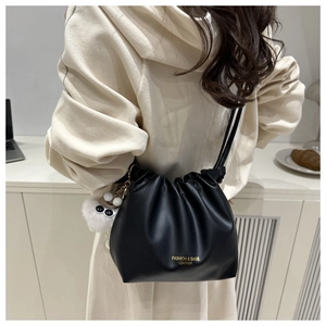 Detail of black drawstring bucket bag with gold lettering and cute plush eye charm