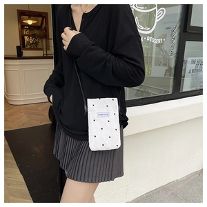 Detail of white fabric crossbody bag with black flower embroidery and Creative Cat tag
