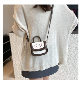 Mini crossbody bag with cherry embroidery and contrasting brown and white panels on a model