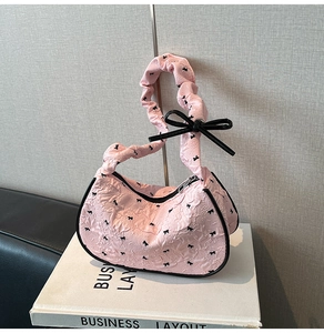 Detail of pink bubble texture fabric on hobo bag with black ribbon bow patterns