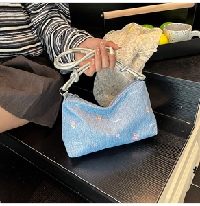 Close-up of denim fabric handbag with pink tulip prints and silver rope shoulder strap