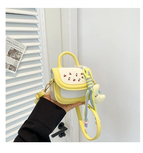 Detail of mini yellow and white crossbody bag with cherry embroidery and moon plush charm