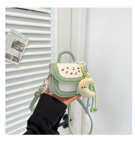 Detail of mint green cherry print handbag with cute moon plush charm and braided strap
