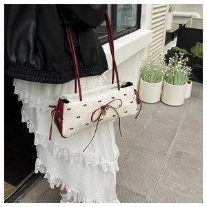 Détail du sac à bandoulière crème avec motifs nœuds rouges et pendentif coeur en métal