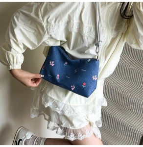 Detailed close-up of a blue denim handbag featuring a delicate pink floral print pattern