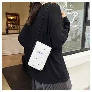 Detailed view of white quilted crossbody bag with black stars and Creative Cat label