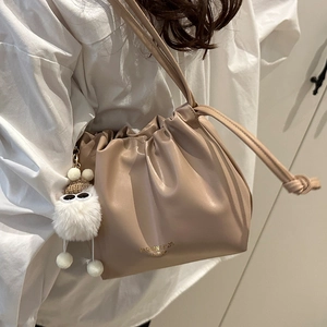 Fashionable khaki drawstring bucket bag with gold lettering and cute plush monster charm