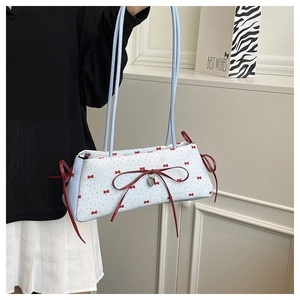 Détail du sac bandoulière bleu clair avec pois rouges, nœud et pendentif en cœur