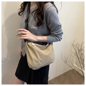 Detail of khaki waterproof fabric shoulder bag with crescent shape and white zipper