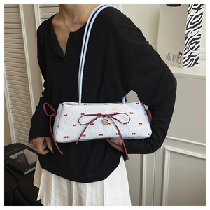 Détail du sac à bandoulière avec nœud en ruban rouge, pendentif cœur et pois vintage