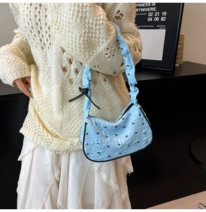 Detail of light blue hobo bag with black bow prints and ruffled shoulder strap
